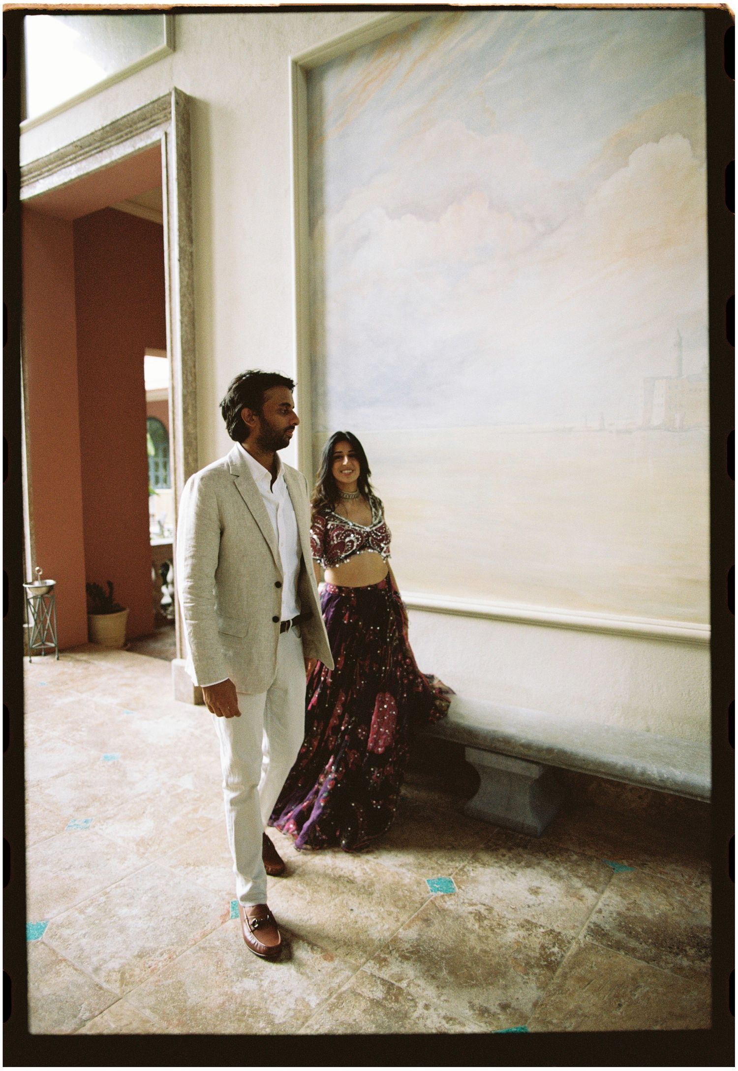 Elina and Jag walking together through a palace interior, photographed on film.