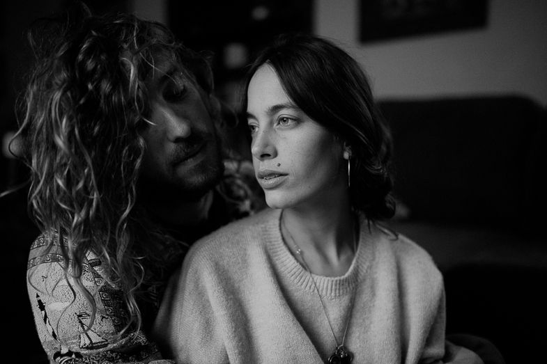 Black and white intimate portrait of two people sharing a quiet moment on a couch.