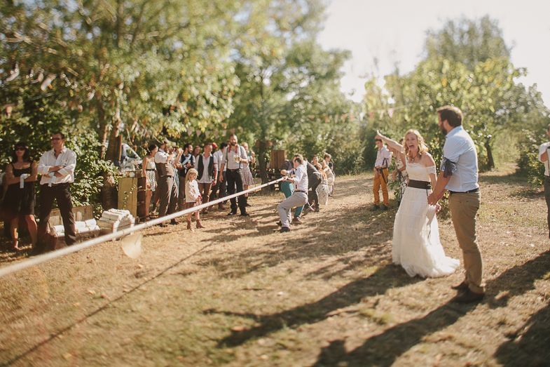 An outdoor wedding ceremony in a sunlit garden with string lights and decorations.