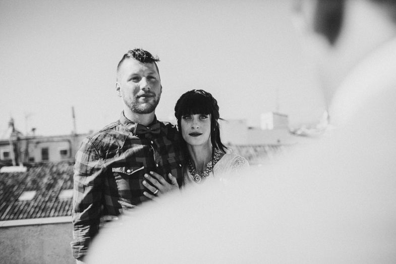 Black and white portrait showing a couple embracing against a city backdrop.