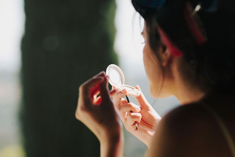 Someone applying makeup in natural window light.