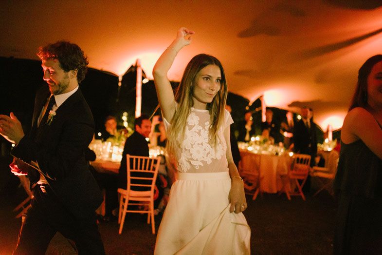 Dancing guests enjoy the evening reception under warm lighting and candlelit atmosphere.