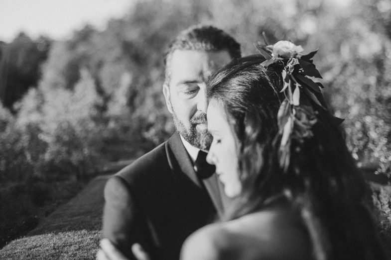 An intimate black and white portrait of a wedding couple in an outdoor garden setting.