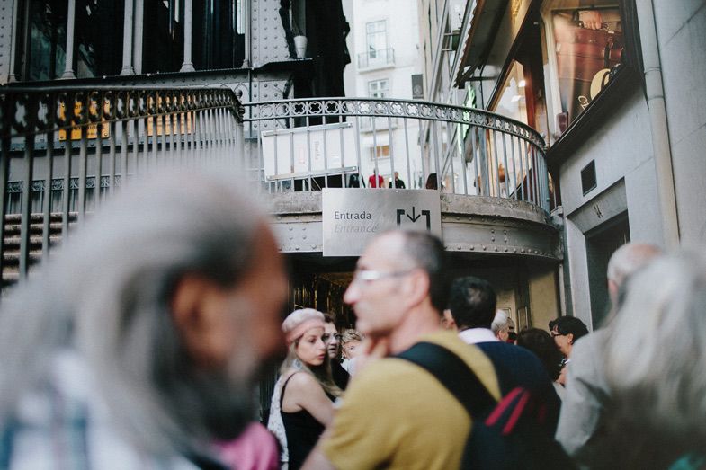 Crowded elevator entrance with curved architecture and people waiting in line.
