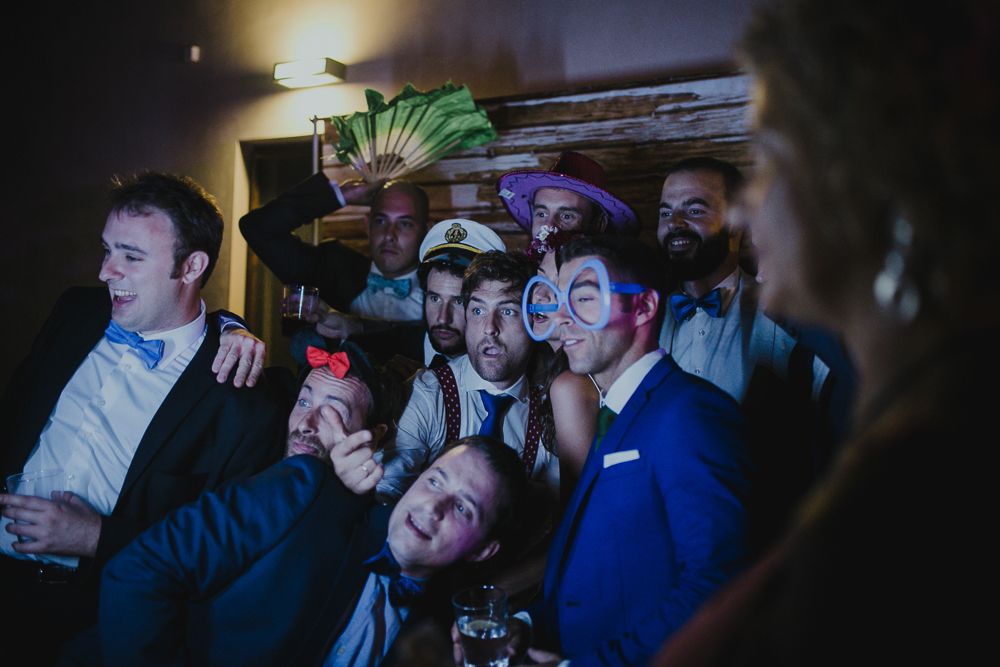 Crowd of people enjoying drinks and laughing at a party with dramatic lighting.