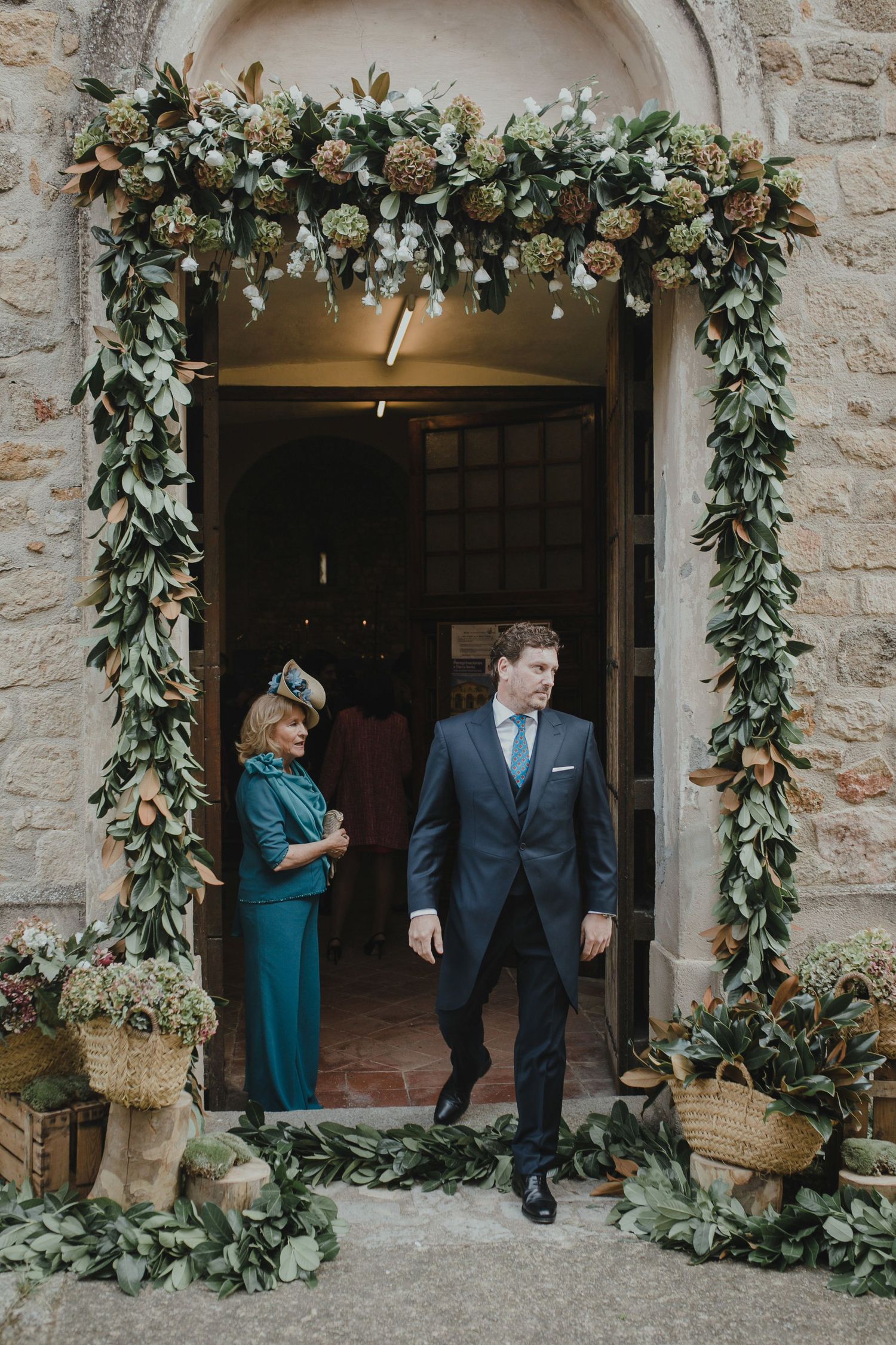 Stone doorway decorated with elegant floral arch and greenery for wedding ceremony.