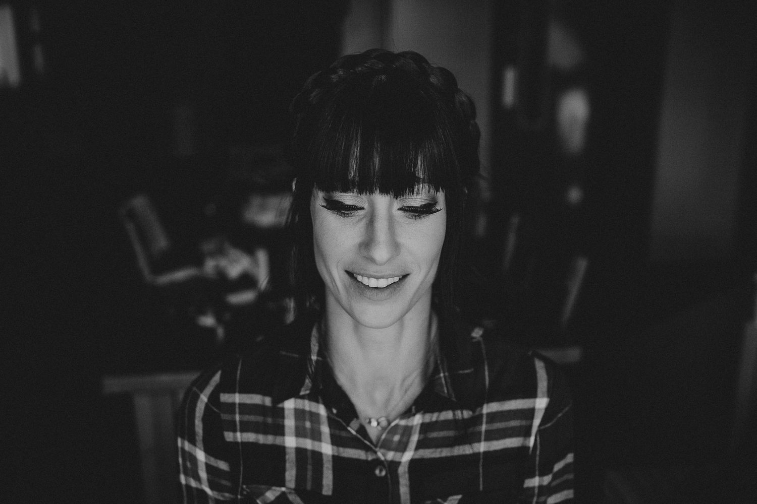 Black and white portrait of someone wearing a plaid shirt while smiling.