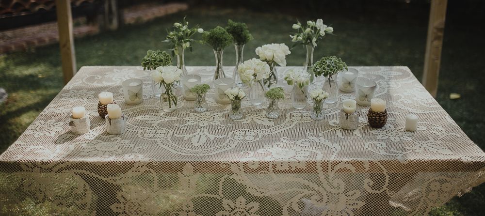 An elegantly set wedding table with white flowers and delicate decor on a textured tablecloth.