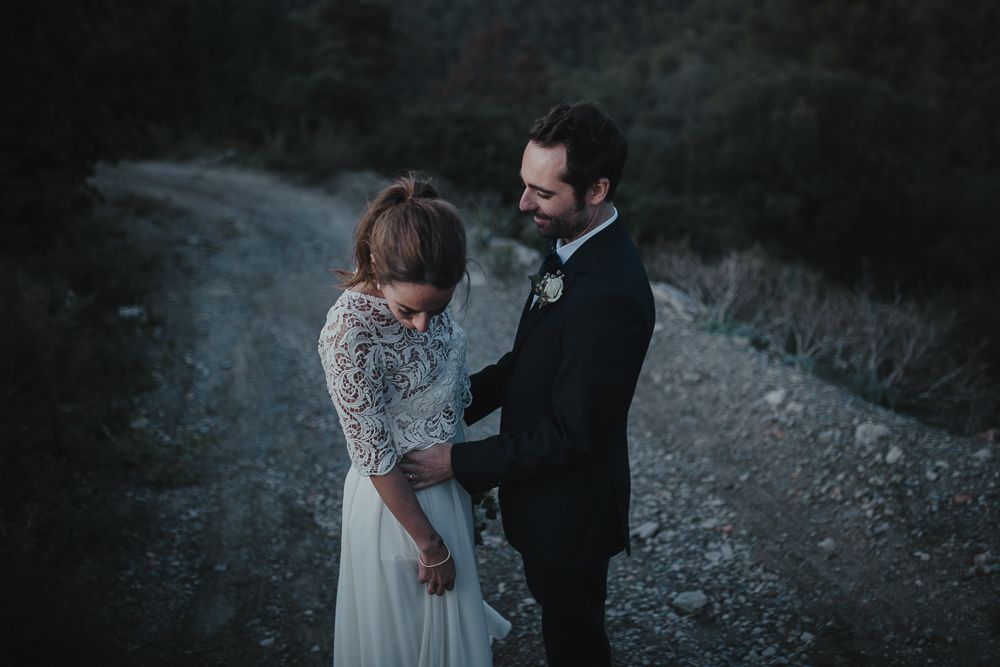 Candid wedding moment shared between couple on a mountain path.