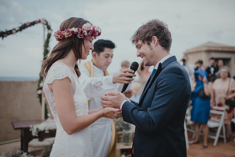 A couple exchanges vows during their outdoor wedding ceremony with guests watching in the background.