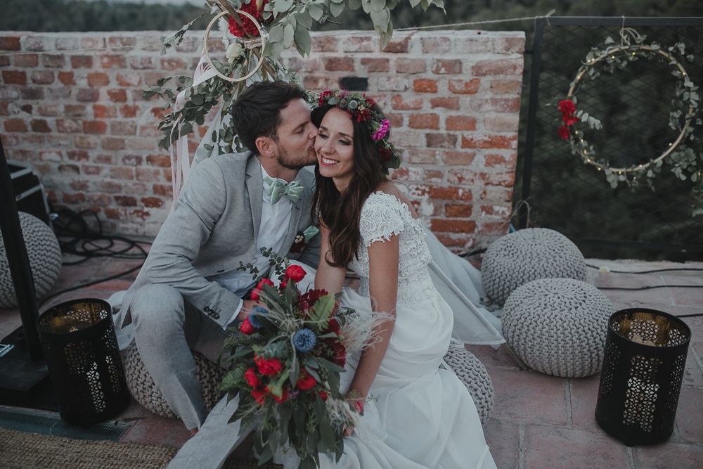 Intimate wedding moment captured on a rustic brick terrace with decorative floral arrangements.