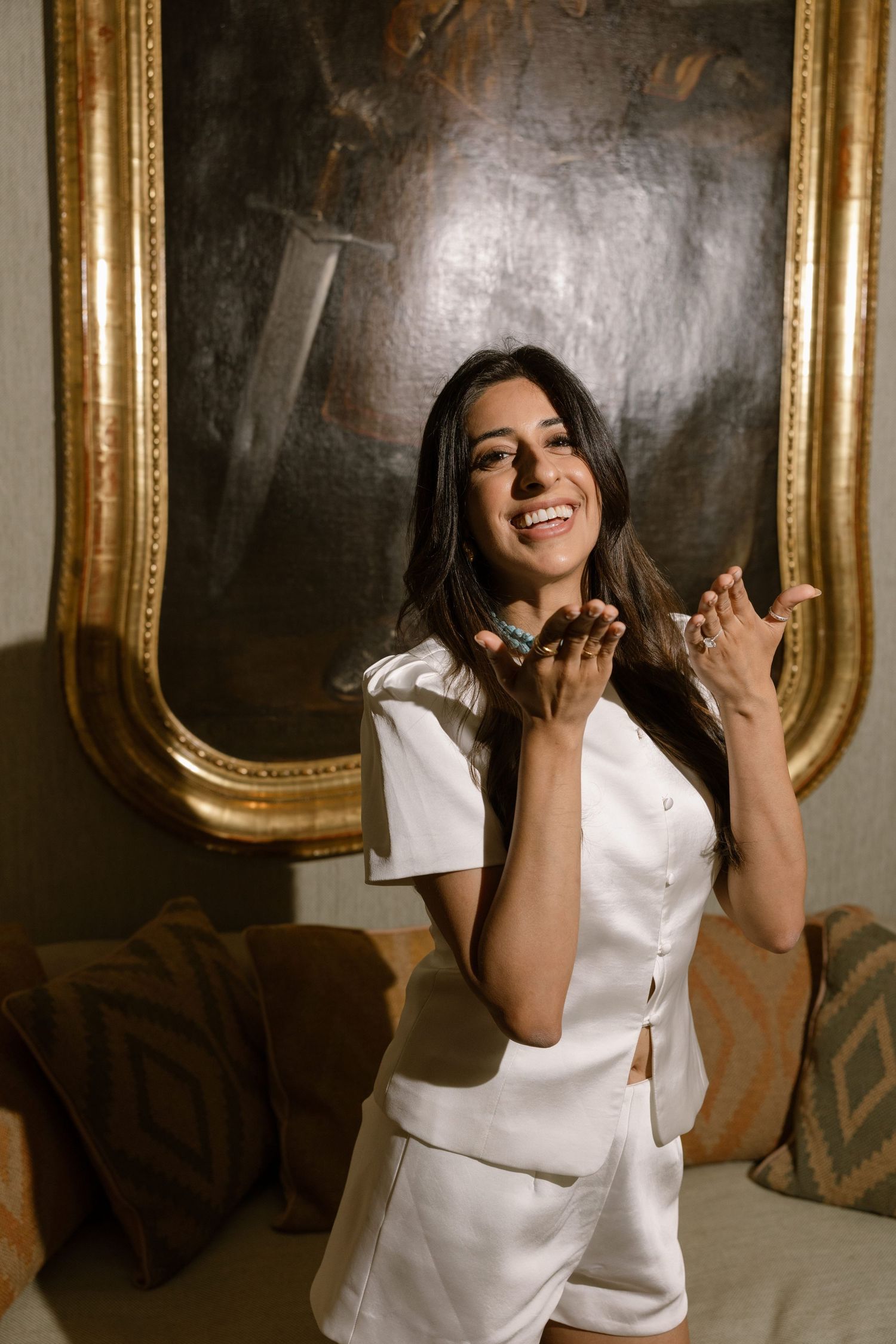 Elina smiling inside the palace in a short white dress.