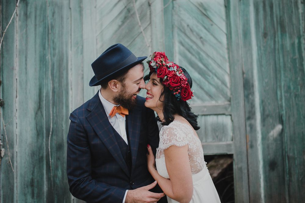 Vintage-styled wedding portrait with turquoise doors and red floral crown.