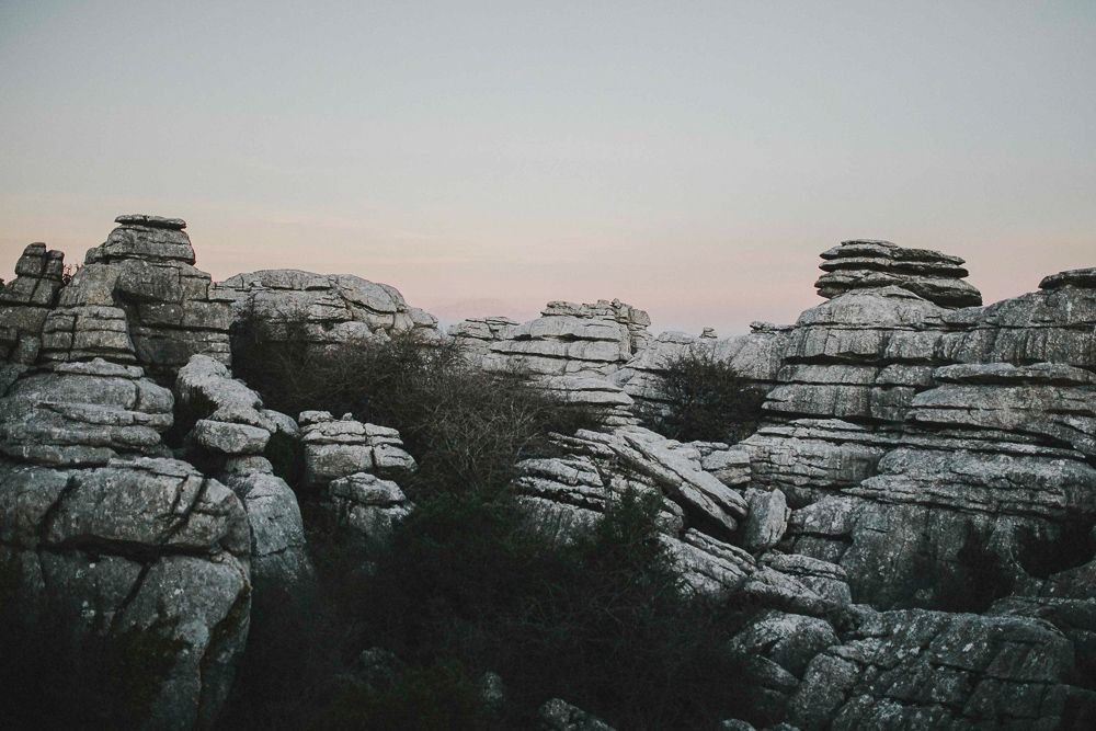 Natural rock formations stand against a dusky sky in a desert landscape.