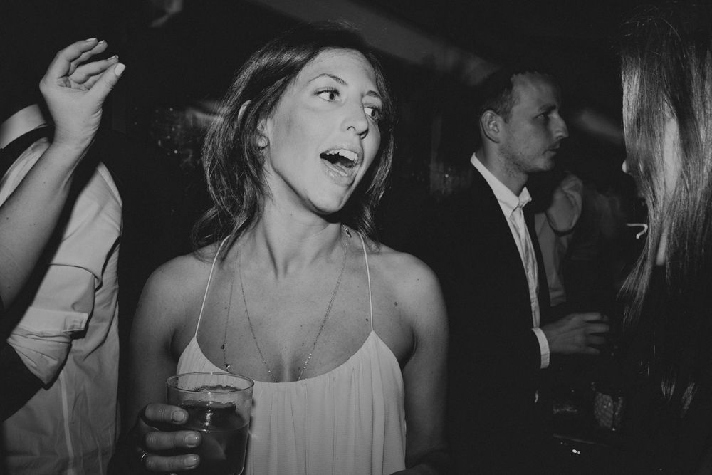Woman in white dress dancing enthusiastically at a nightclub party.