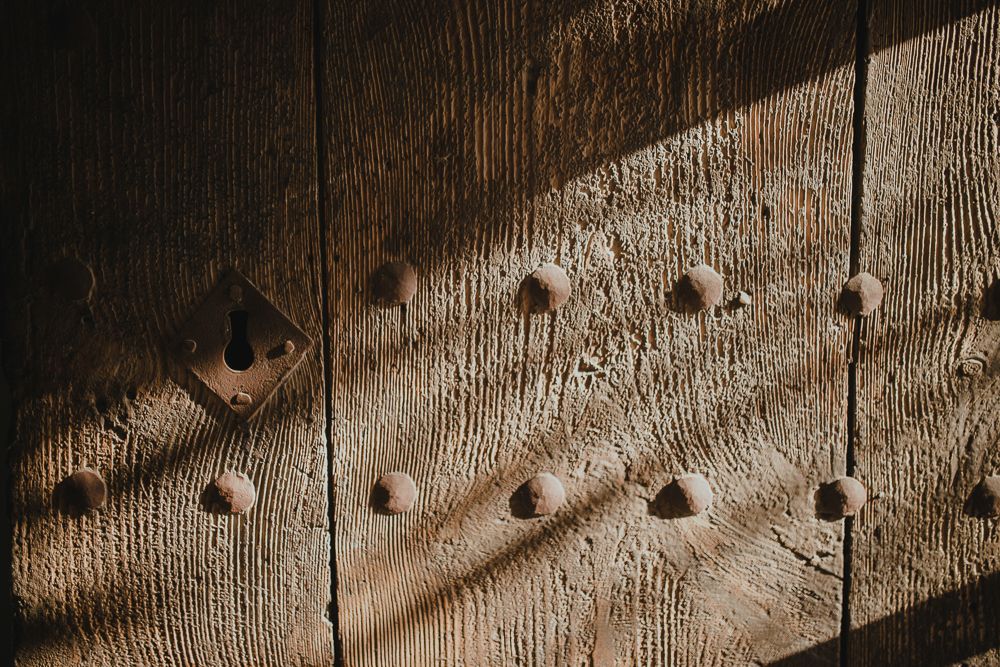 Wooden planks with metal rivets casting dramatic diagonal shadows.