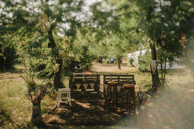 Rustic outdoor wedding seating arrangement with wooden benches in a garden setting.