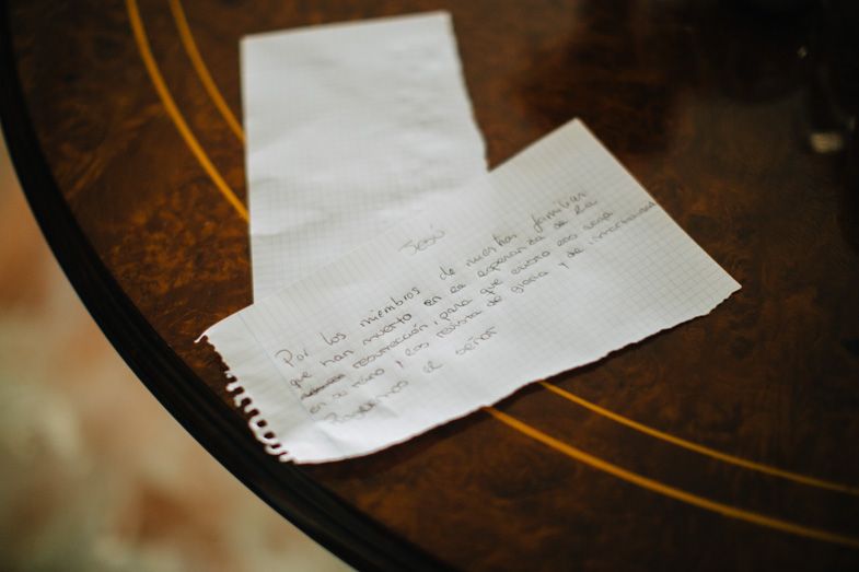 A handwritten note sits on a dark wooden surface with circular patterns.