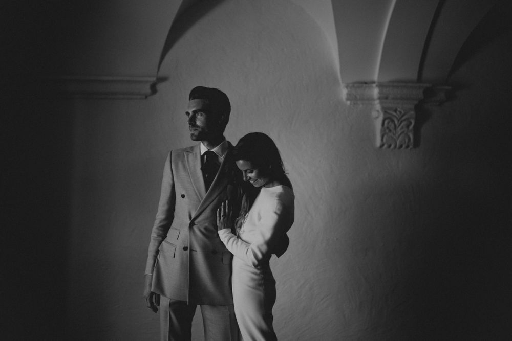 Artistic black and white portrait of couple under arched architectural details.