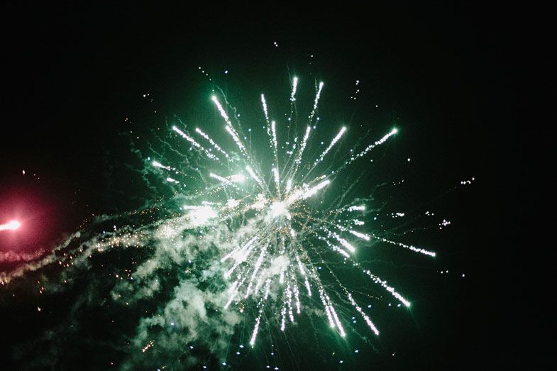White fireworks burst against a dark night sky during a celebration.