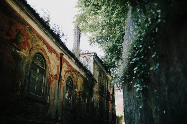 Gothic style architecture with arched windows and ivy covered walls in moody lighting.