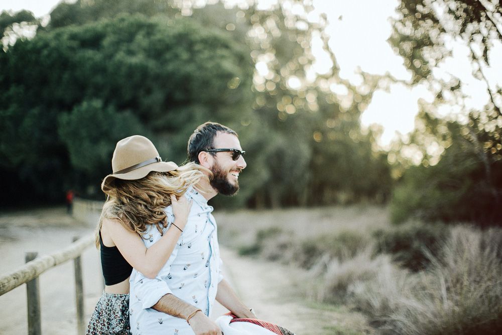 A couple enjoys a sunset moment on a rustic fence.