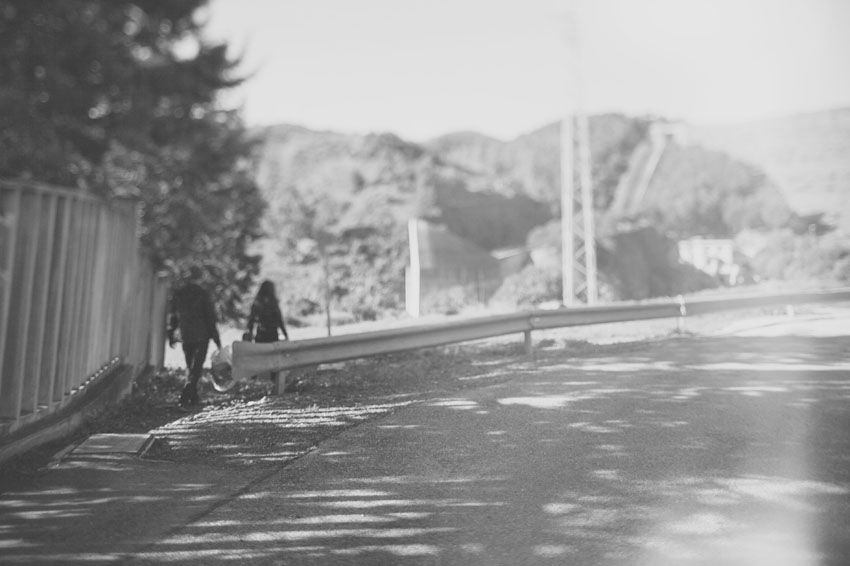 Black and white photo of people walking along a path with mountains in the background.