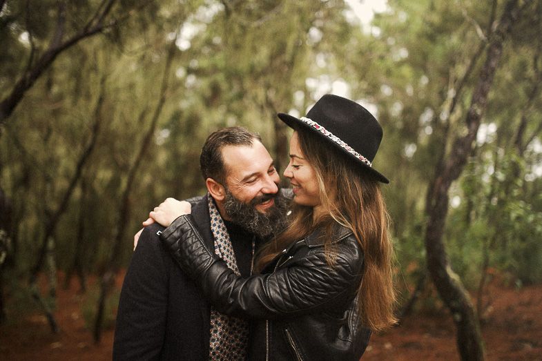 A couple shares a joyful moment together in an autumn forest setting.