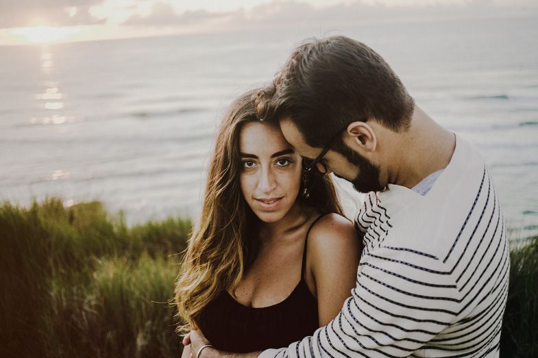 A couple shares an intimate moment at sunset overlooking the ocean.