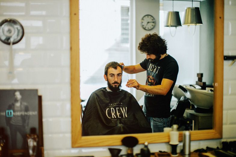 A professional haircut in progress at a modern barbershop with stylish lighting and mirrors.