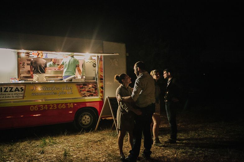 People gathered around a brightly lit food truck at night for refreshments.