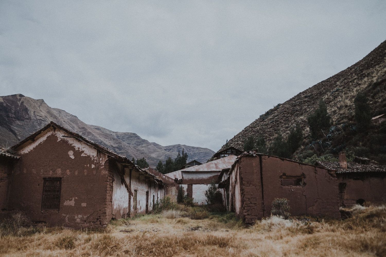 Row of abandoned adobe buildings in a remote mountain valley.