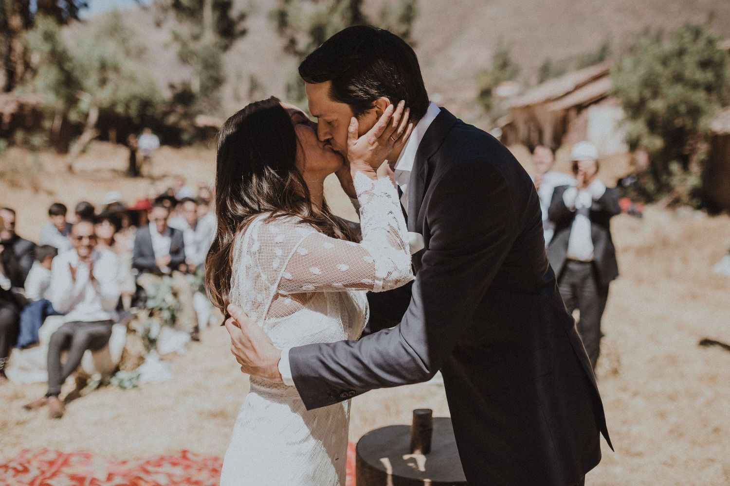 A romantic first kiss between newlyweds at a scenic outdoor mountain wedding ceremony.