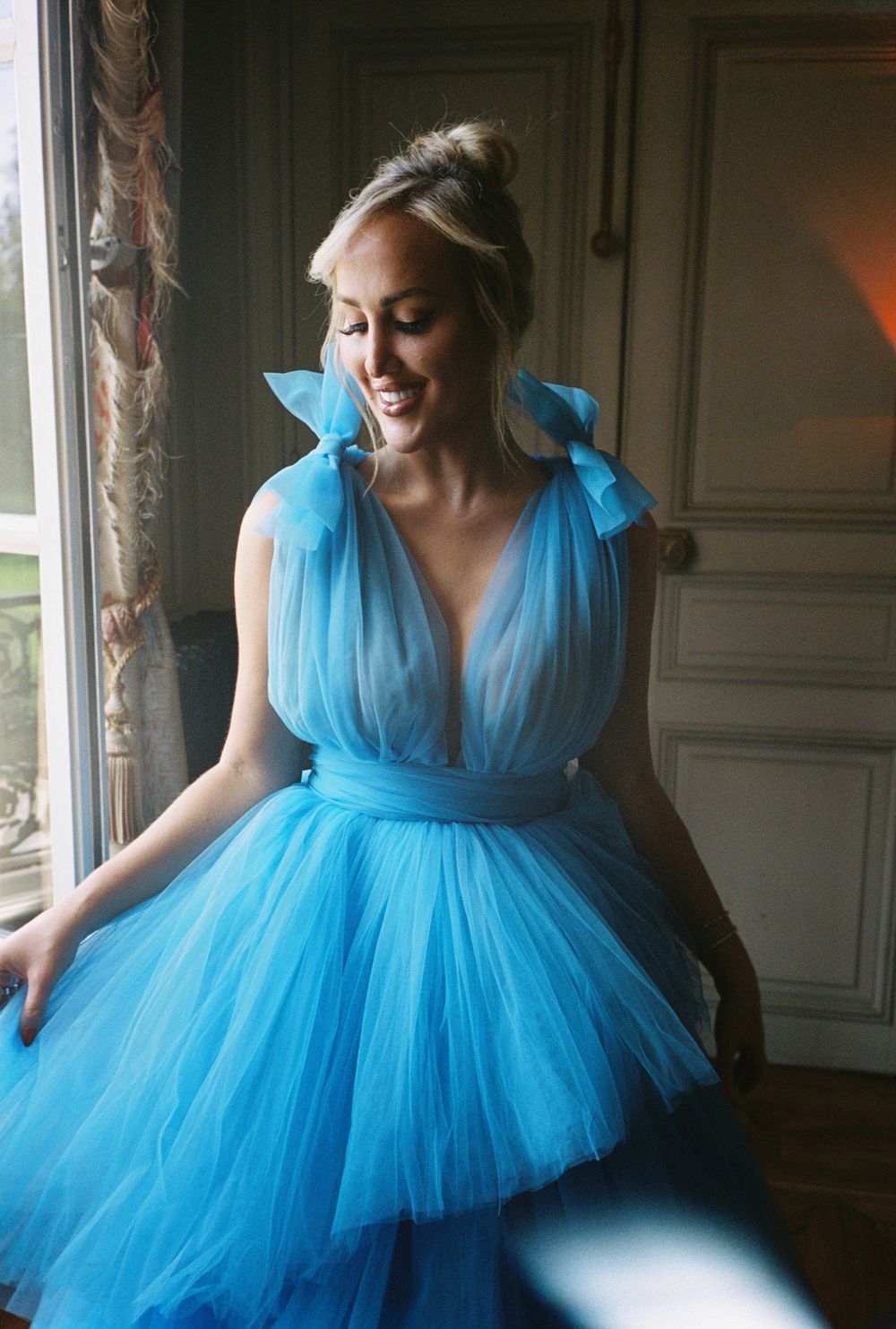 Flowing bright blue tulle dress with ruffles twirling in an elegant indoor setting.