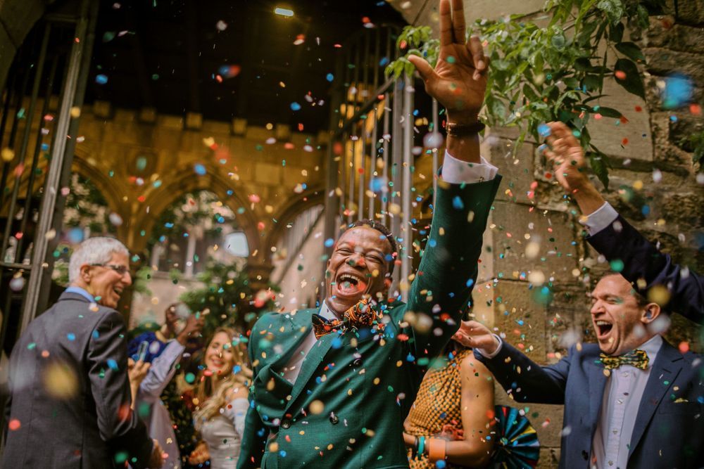 Wedding celebration with guests throwing gold confetti in evening light.