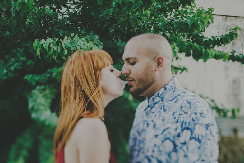 A romantic moment shared between a couple in front of lush green foliage.