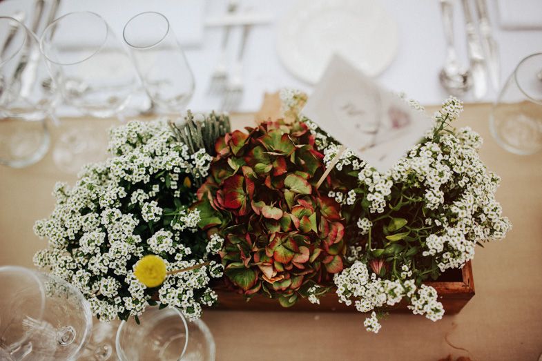 Wedding table centerpiece featuring baby's breath and hydrangea flowers in rustic arrangement.