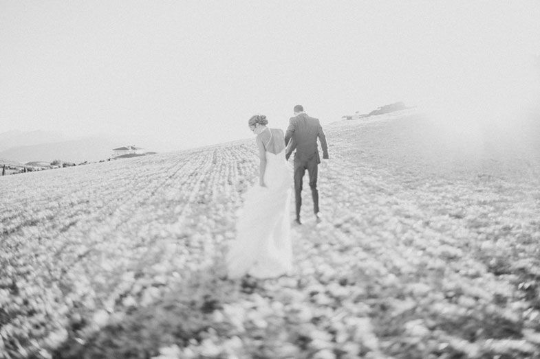 Two silhouettes walking through a misty field during golden hour.