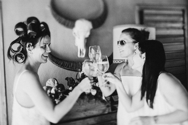 Two people toasting with wine glasses in front of a wall decorated with animal skulls.