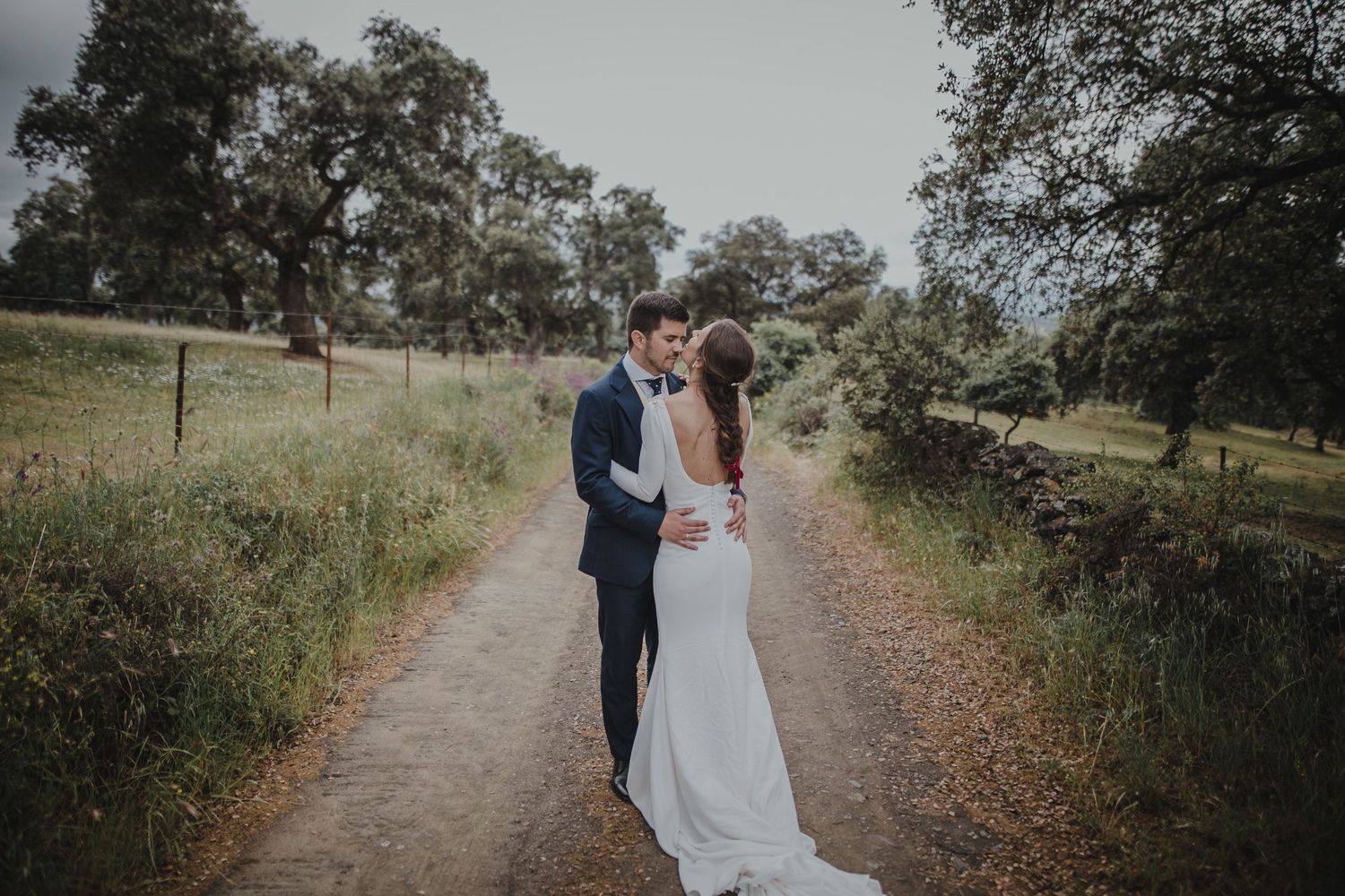 A tender moment between newlyweds on a country road surrounded by oak trees.