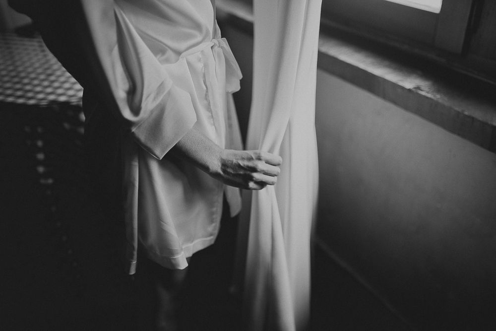 Close-up of hands holding white fabric near a window in black and white.