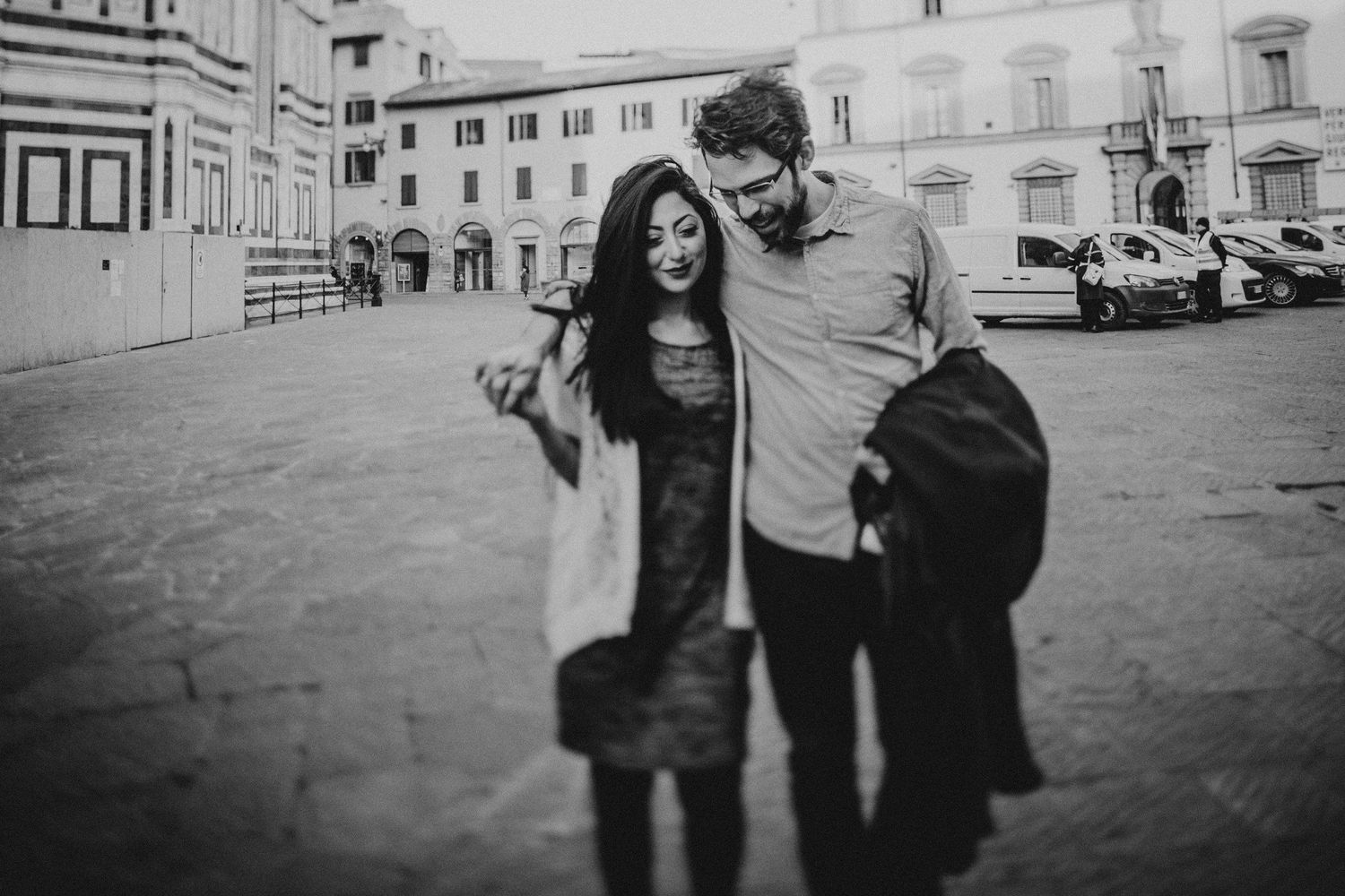 Black and white photo of happy couple walking in Italian plaza.