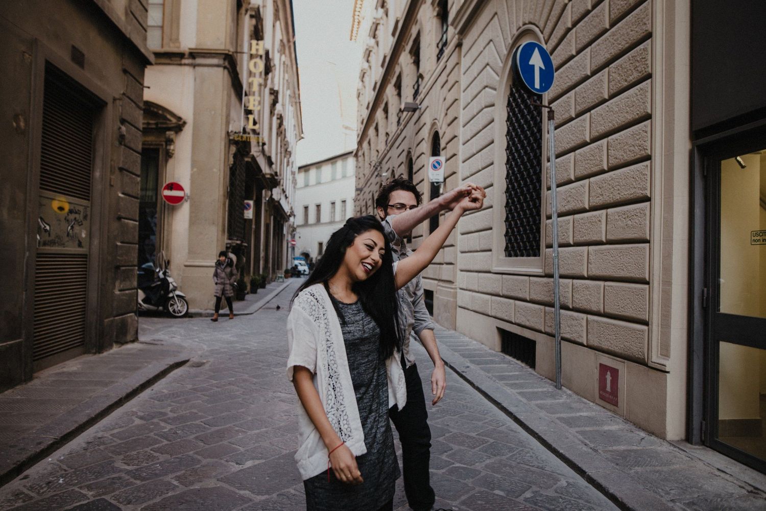 A playful couple dancing and laughing together on an Italian street.
