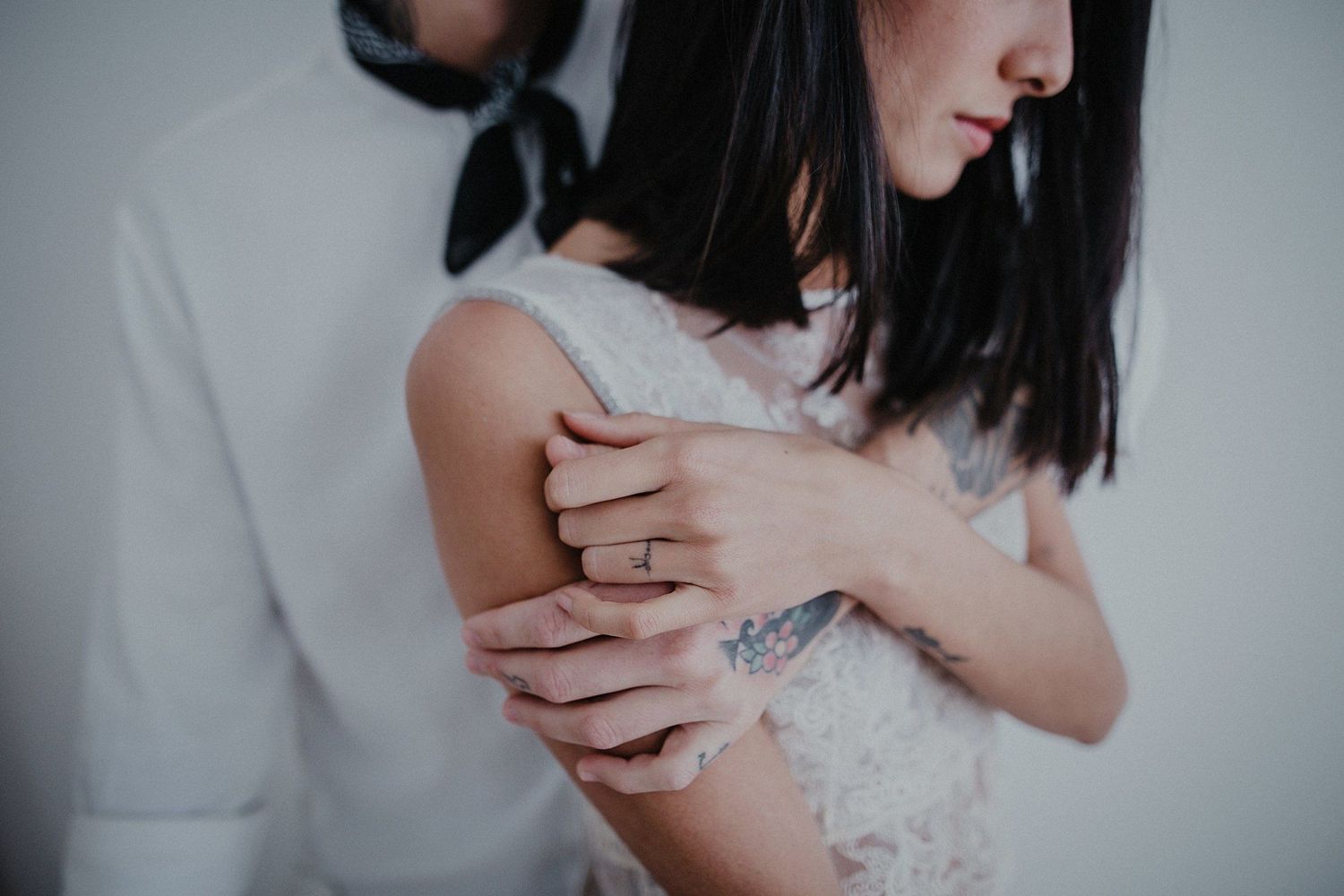 Intimate close-up photograph showing gentle embrace and tattoo details.