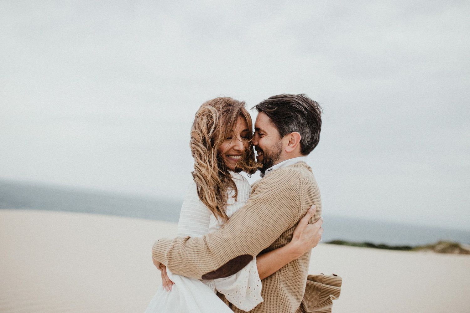 Tender romantic moment between couple on sandy beach landscape.
