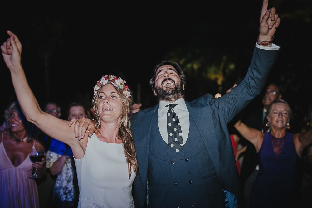 Celebratory moment at an outdoor wedding reception with hands raised in joy.