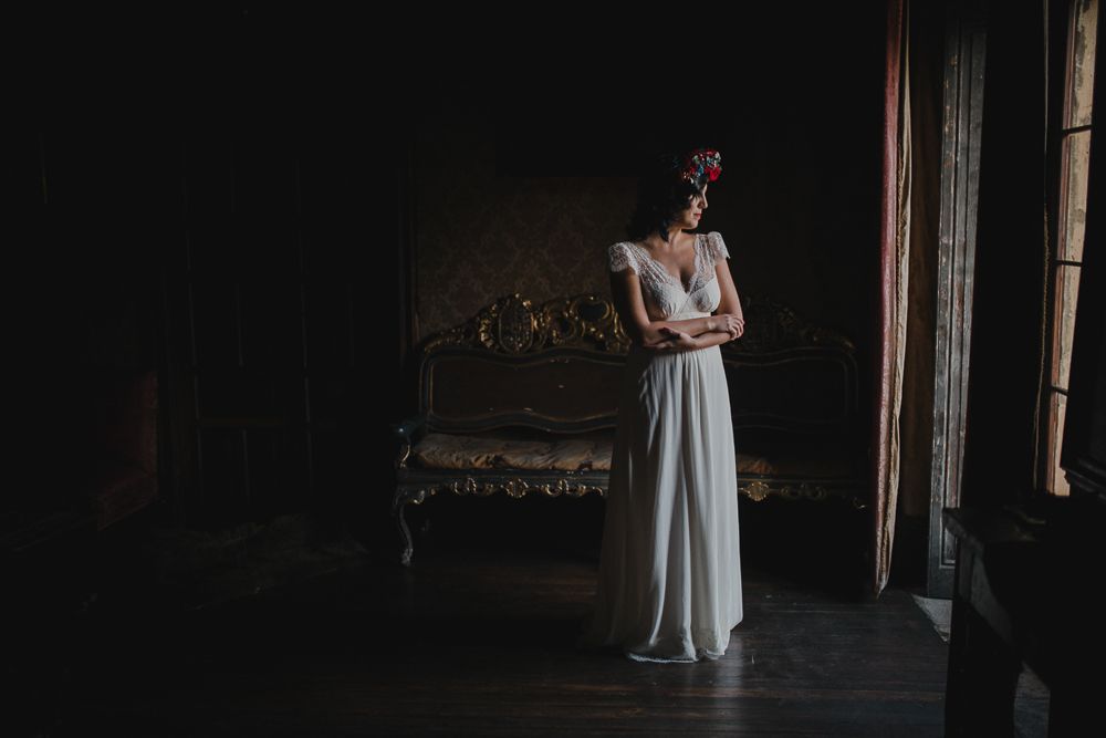 An elegant wedding dress photograph in a moody, vintage room with antique furniture.