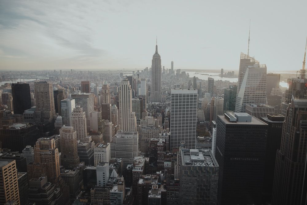 Moody cityscape view of Manhattan showing the Empire State Building and surrounding skyscrapers.