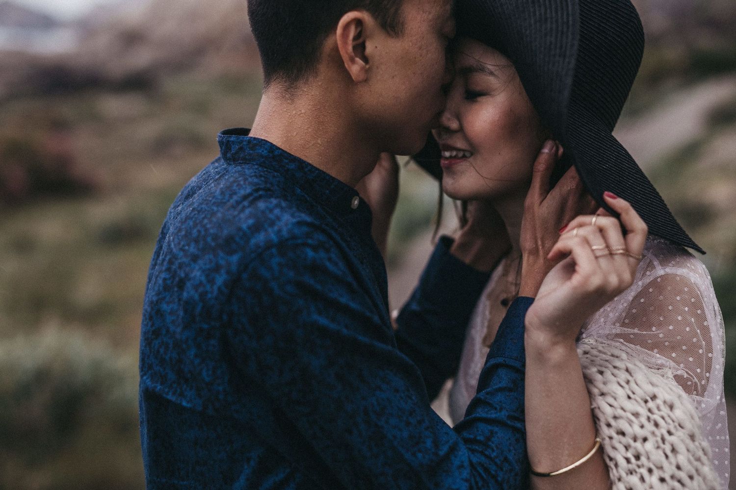 Intimate close-up of couple embracing in nature wearing navy blue and white lace.