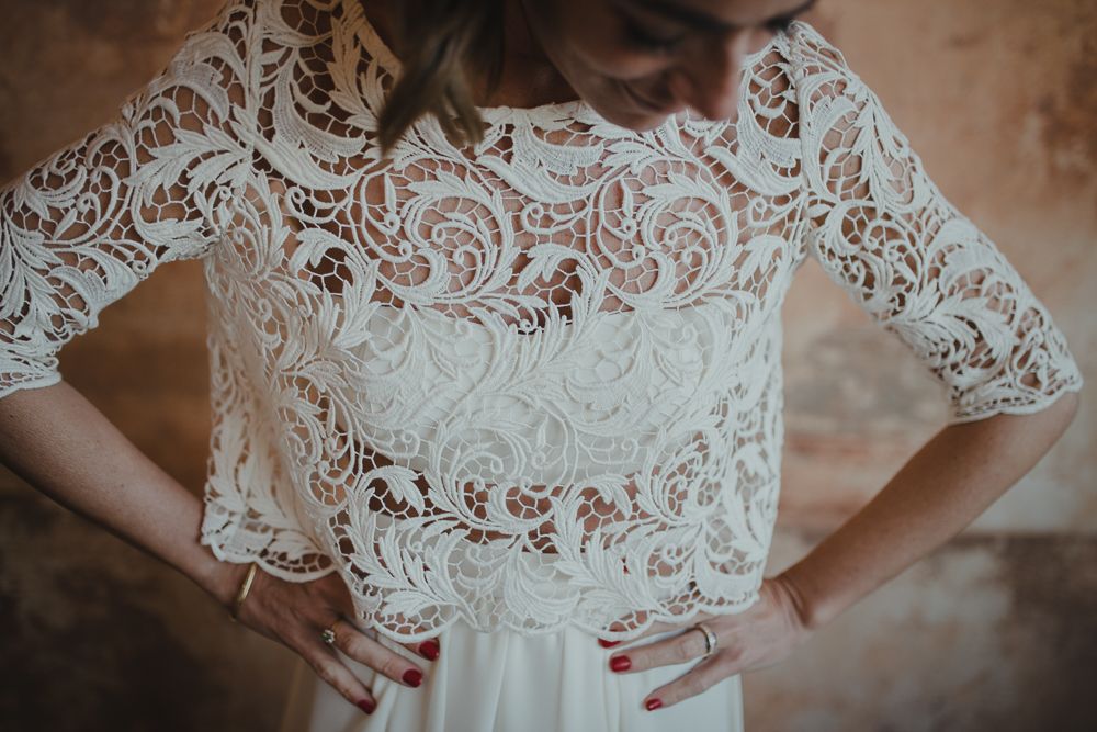 Detailed view of an intricate white lace crop top wedding dress bodice with delicate floral patterns.